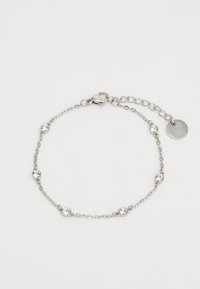 Bracelet en métal argenté ornée d'accents en cristal clair circulaires, d'un fermoir en forme de homard et d'une extension ajustable avec une étiquette circulaire.