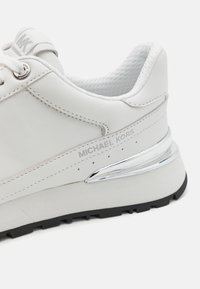 Weiße Leder sneakers mit silbernem Logo, durchbrochenen Akzenten, gepolstertem Innenfutter und schwarzer Gummisohle.