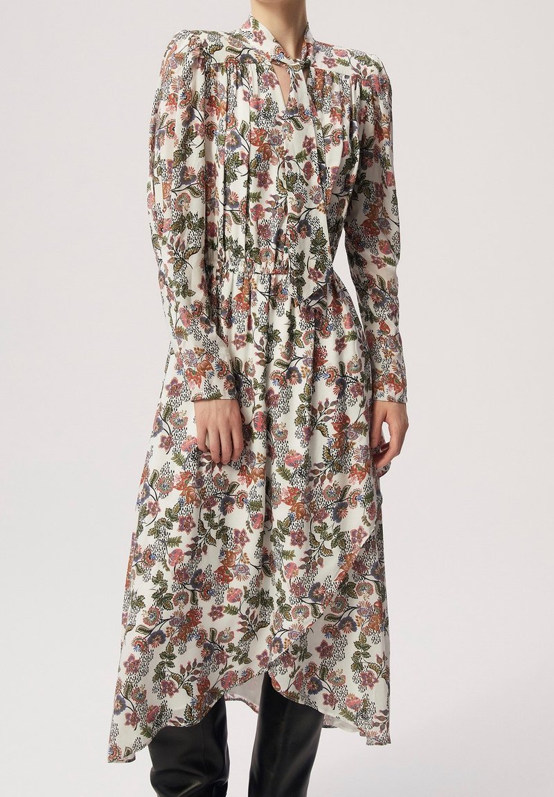 Šaty s květinovým potiskem mají bílý základ, nabírané rukávy, výřez na krku a asymetrický lem. Lehká tkanina s živými vzory.