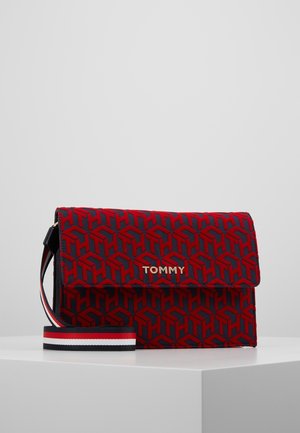 Prostokątna czerwona i granatowa torebka na ramię z powtarzającym się geometrycznym wzorem, złotym logo TOMMY i paskiem na ramię z regulowaną długością w paski.