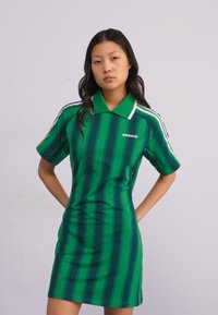 Rochie polo verde cu dungi, cu mâneci scurte, având un guler solid și dungi laterale albe. Materialul este neted și ușor.