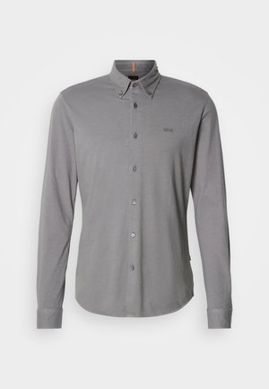 Pelēkšas garās piedurknes krekls izgatavots no kokvilnas, ar pogu aizdari, norādītu apkakli, nelielu logotipa akcentu un kontrastējošu oranžu kakla etiķeti.