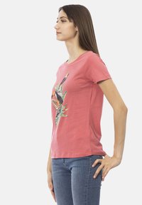 Roze katoenen T-shirt met korte mouwen, met een kleurrijke toekanafbeelding en een tropisch loofontwerp in het midden.