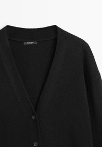 Czarny kardigan wykonany z miękkiego materiału, z dekoltem w serek, długimi rękawami i trzema guzikami z przodu. Prosty design o gładkiej fakturze.