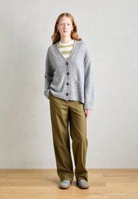 Gray knit cardigan with a V-neck, button front, and two pockets, paired with olive green trousers and gray shoes, showcasing a relaxed fit.