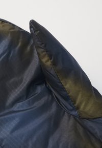 Navy blue quilted fabric with a smooth texture and a slight sheen. Features a pointed top edge and flat seams. Subtle pattern visible.