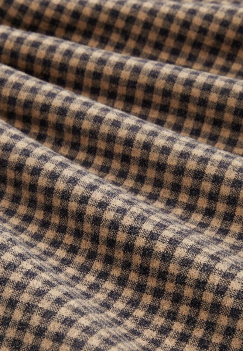 Wollstoff mit einer strukturierten Oberfläche, featuring ein navyblaues und beiges karriertes Muster, in einer zerknitterten Anordnung.