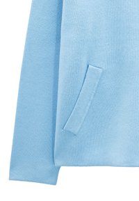 Jasnoniebieski sweter o miękkiej strukturze, z małą, haftowaną kieszonką po boku i luźnym krojem.