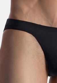 Black swim brief made from smooth fabric, featuring a low-rise cut and wide elastic waistband. The texture appears soft against the skin.