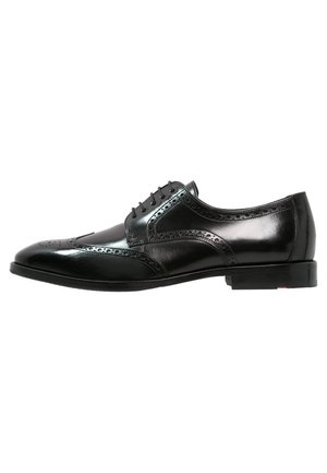 Black leather dress shoe with a glossy finish, wingtip design, brogue detailing, and lace-up closure. Flat sole with minimal heel.