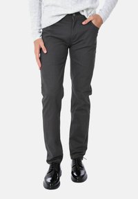 Jeans grigio scuro realizzati in tessuto misto cotone, fit dritto, design a cinque tasche, con chiusura a bottone e dettagli di cucitura sottili. Scarpe nere in abbinamento.