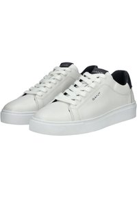 Sneakers bianchi in pelle con una texture liscia, punta rotonda, suola piatta in gomma bianca e un accento in pelle nera nel tallone. Lacci e logo sulla linguetta.
