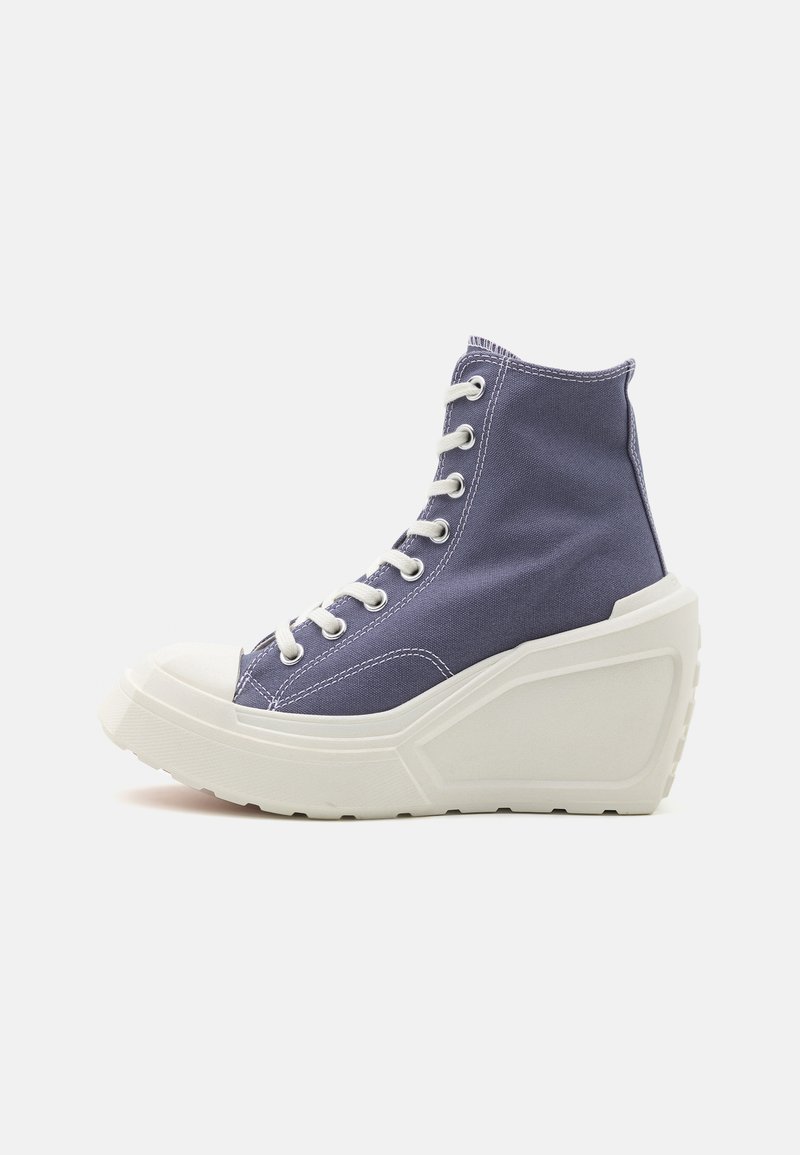 High-top sneakers with a purple canvas upper and white rubber sole. Features include a rounded toe, lace closure, and a wedge heel.