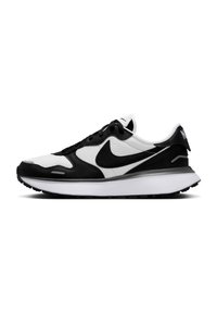 Črne in bele Nike superge s teksturirano usnjeno zgornjico, podložnim ovratnikom in belo srednji podplatom, ki ima črn gumijast podplat.