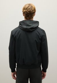 Zwarte bomberjack met capuchon, met een gladde textuur, elastische manchetten en een aansluitende zoom. Subtiel ontwerp zonder zichtbare logo's of patronen.
