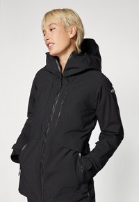 Black waterproof jacket with a high collar, zippered pockets, and adjustable cuffs. Features a sleek design without visible logos.