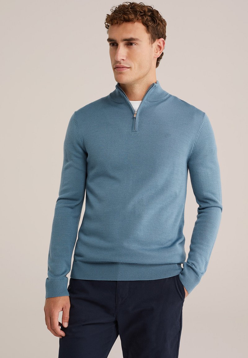 Hele sinine zippidega sviiter pikkade varrukatega ja ribakudumiga varrukate ning alumise äärtega, valmistatud pehmest kudumismaterjalist. Omab neljandiku pikkusega tõmblukk kaeluses.