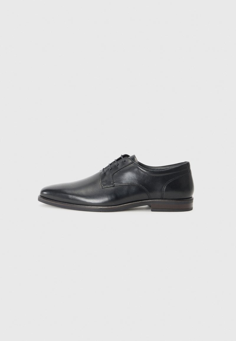Black leather dress shoe with a pointed toe, low heel, and five eyelet lacing. Features smooth texture and minimal stitching details.