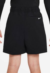 Juodos, lengvos šortai su elastinga juosmeniu, šoninėmis kišenėmis ir maža balta Nike logotipu ant nugaros. Sklandus audinio paviršius.