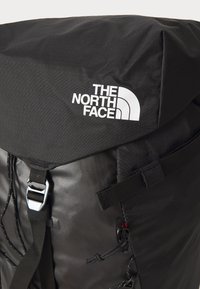 Must svart seljakott koos rullitava ülaosaga ja tekstuurse kanga. Omab reguleeritavaid rihmasid, metallist pannalit ja The North Face'i logo selgelt nähtaval.