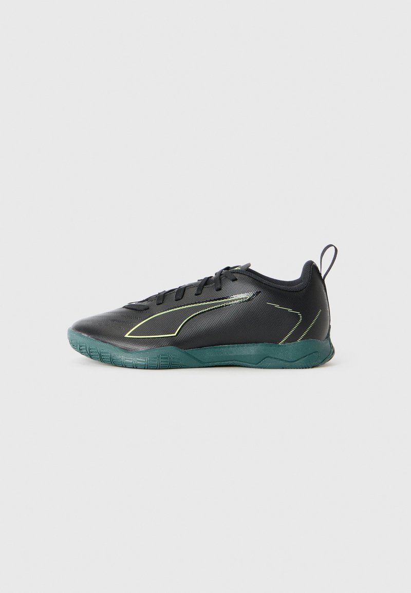 Scarpa sportiva nera con una tomaia testurizzata, suola verde a contrasto e accenti gialli. Presenta un design con lacci e un tassello sul retro per il sollevamento.