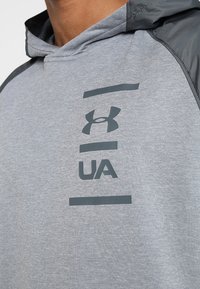 Szara bluza z kapturem, z ciemnoszarymi logo i liniami. Gładki materiał z kontrastowymi rękawami, luźny fason.