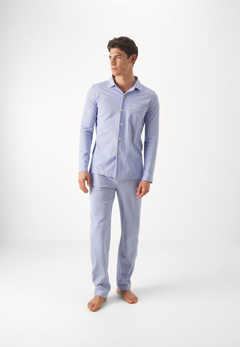 Light blue cotton pajama set featuring a button-up long-sleeve shirt with a chest pocket and matching pants. Soft texture, tailored fit.