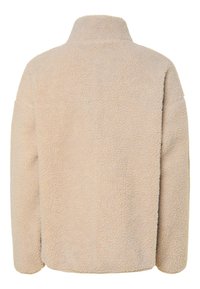 Jachetă din fleece bej, cu guler înalt, suprafață moale la atingere, umeri căzuți și croială lejeră, fără fermoare vizibile sau buzunare.