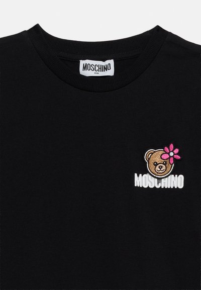 Παιδικό μπλουζάκι Moschino σε μαύρο χρώμα με στρογγυλή λαιμόκοψη, διακοσμημένο με εφαρμογή κεφαλής αρκουδάκιου με ροζ λουλούδι και λευκό λογότυπο Moschino στο στήθος.