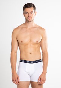 White boxer shorts with a black waistband featuring "CR7" logo. The fabric appears smooth and stretchy. Model has a neutral pose.