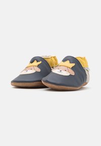 Chaussures en cuir pour bébé en bleu marine avec un adorable design de visage de chien. Accents jaunes à l'arrière, semelle souple et forme de pied rond.