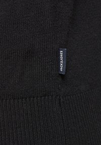 Maglione nero a maglia con texture a coste, con un piccolo etichetta blu e bianca con la scritta "JACK & JONES" cucita di lato.