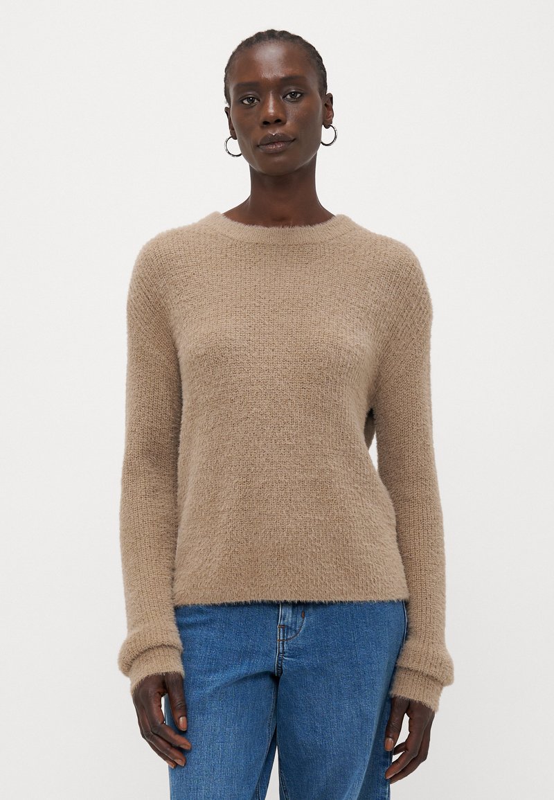 Maglione beige in maglia con scollo rotondo, maniche lunghe e finitura testurizzata. Abbinato a jeans blu.
