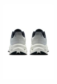 Graue Sportschuhe mit strukturiertem Obermaterial, weißer Zwischensohle und dunkel gefärbter Außensohle. Verfügt über einen gepolsterten Kragen und minimalen Markenaufdruck.