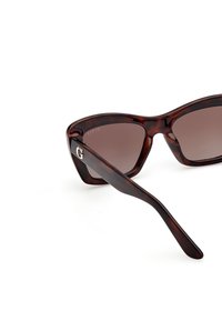Tortoiseshell sunglasses with a thick frame, gradient brown lenses, and gold 'G' logo on the side. Sleek arm design with smooth texture.