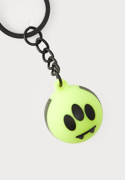 Portachiavi in silicone verde brillante con design rotondo, dotato di tre occhi neri e piccoli denti appuntiti, attaccato a una catena e anello in metallo nero.