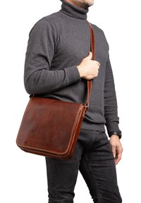 Borsa a messanger in pelle marrone con una finitura liscia e cuciture a contrasto, dotata di una tracolla regolabile e chiusura a soffietto.