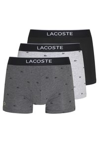 Three pairs of Lacoste boxer briefs: black, gray with small logos, and light gray, featuring elastic waistbands with "LACOSTE" lettering.
