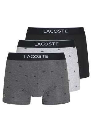 Trys Lacoste vyriškų trumpikių poros: juodos, pilkos su mažomis logotipų detalėmis ir šviesiai pilkos, su elastingais juosmens diržais, ant kurių užrašyta "LACOSTE".