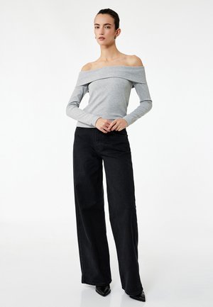 Grå off-shoulder langærmet top parret med højderet sorte brede bukser. Glat stof med minimalistisk design.