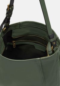 Sac seau en cuir vert avec des ferrures dorées, poches zippées et une texture lisse. L'intérieur est doté d'une doublure noire.