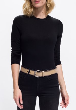 Haut noir à manches longues associé à un jean noir taille haute et une ceinture beige avec une grande boucle en argent.