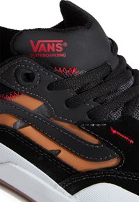 Baskets en daim noir et maille, avec des accents rouges, des lacets ronds et une semelle en caoutchouc blanche. Logo audacieux sur la languette.