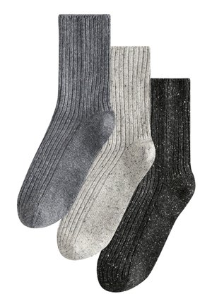 Trois paires de chaussettes en tricot : gris foncé, gris clair avec des speckles, et noir avec des speckles. Chacune a une texture côtelée et une forme de chaussette standard.