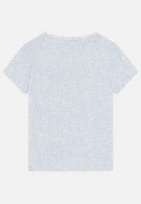 T-shirt bleu clair à manches courtes avec un motif floral. Encolure arrondie avec un détail de bouton au dos. Tissu doux et léger.