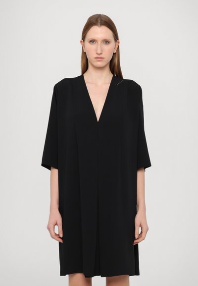 Indumento nero con scollatura a V profonda e maniche corte, realizzato in tessuto liscio. Presenta un design minimalista con una silhouette pulita.