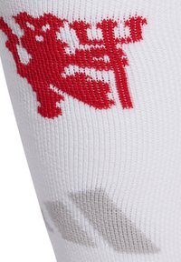 Calcetín deportivo blanco con logo y diseño rojo, con una textura suave y ajuste ceñido, ideal para el rendimiento y la comodidad.