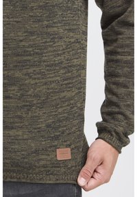 Maglione a collo alto verde oliva lavorato a maglia con motivo testurizzato, dotato di un'etichetta in pelle marrone all'orlo. Vestibilità slim con maniche lunghe.