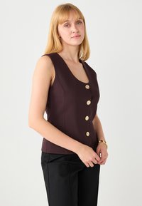 Mauve mouwloze top met een diepe ronde halslijn en vijf gouden decoratieve knopen aan de voorkant. Soepele textuur en nauwsluitend ontwerp.