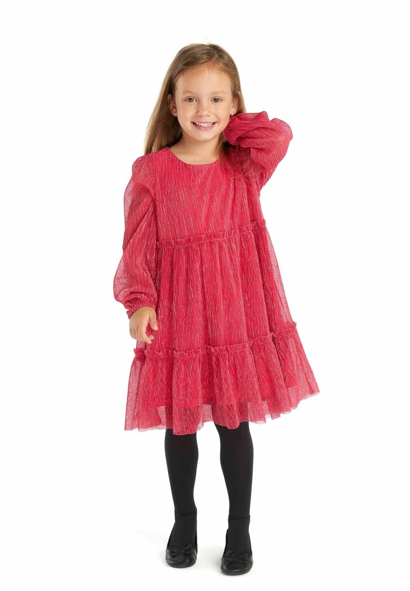 Robe rouge à manches longues avec une jupe à volants en couches et un tissu texturé. Assortie avec des collants noirs et des chaussures. Encolure ronde simple.